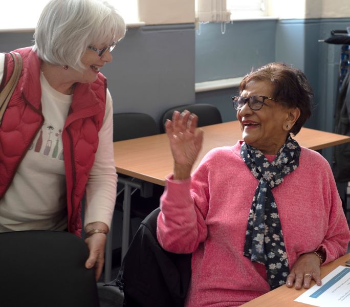 Two carers greet each other at the start of a Carers Support Group