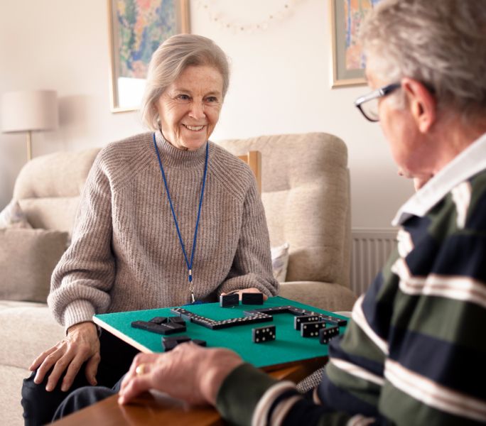 A Carers Break Service volunteer plays dominoes with a cared-for man