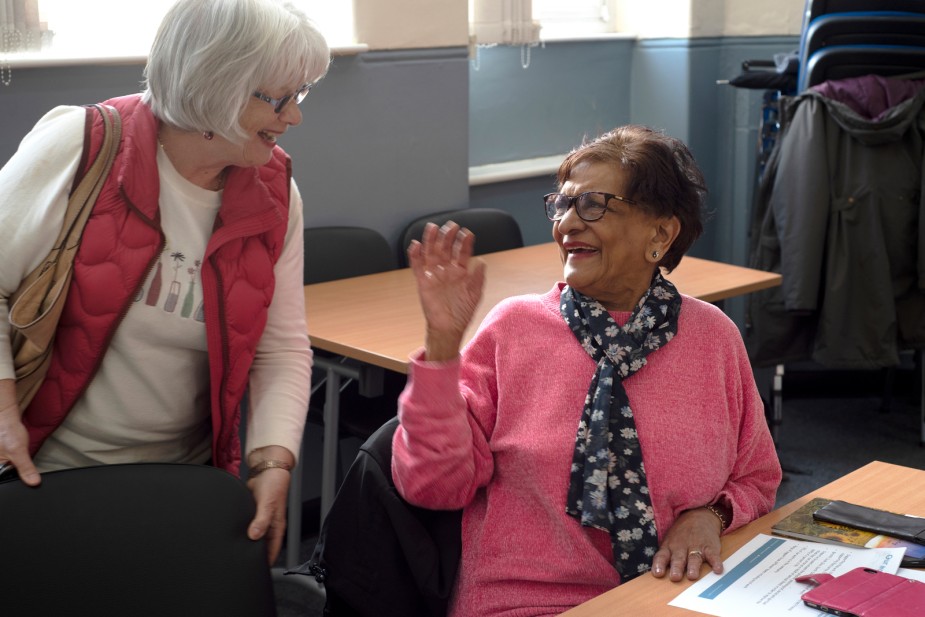 Two carers greet each other before a Carers Support Group meeting