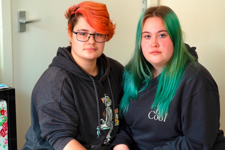 Two young people sit looking at the camera