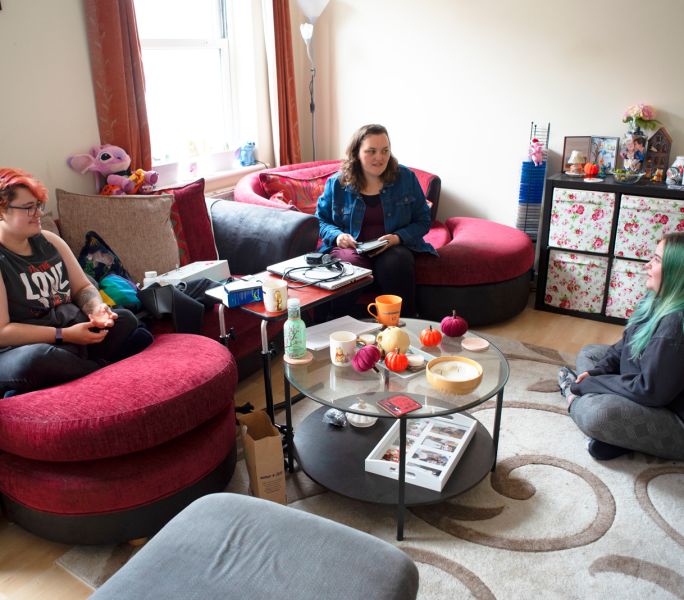 A group of young adult carers sit around chatting with each other