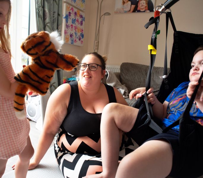 A woman and her disabled son using a hoist in their front room