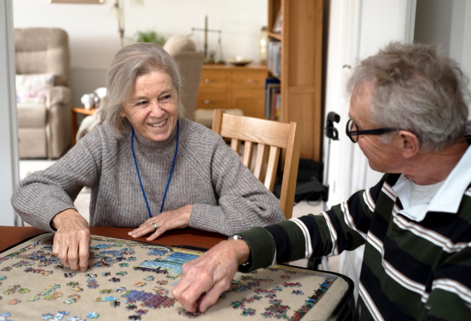 A volunteer doing a puzzle with a cared-for as part of our Carer's Break Service