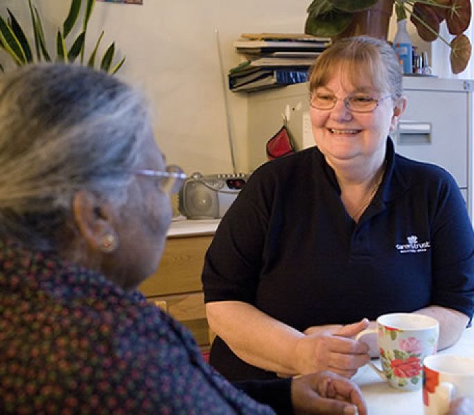 A care worker smiles at an older Asian cared-for