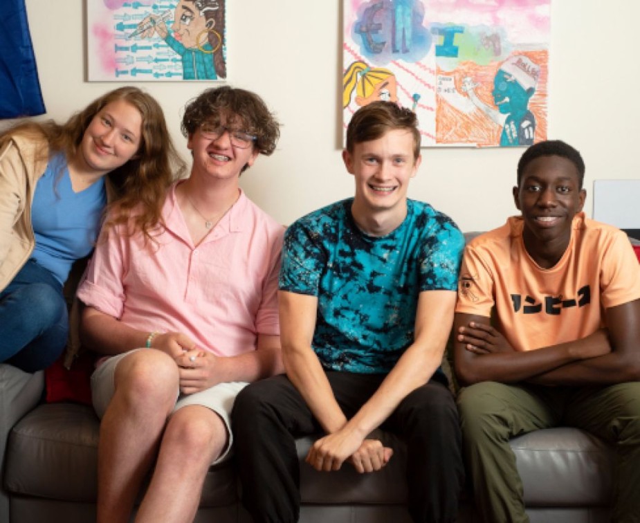 Four happy looking young carers sit on a sofa together