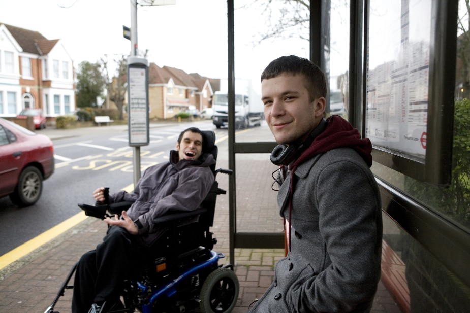 A young man and his disabled brother waiting for a bus