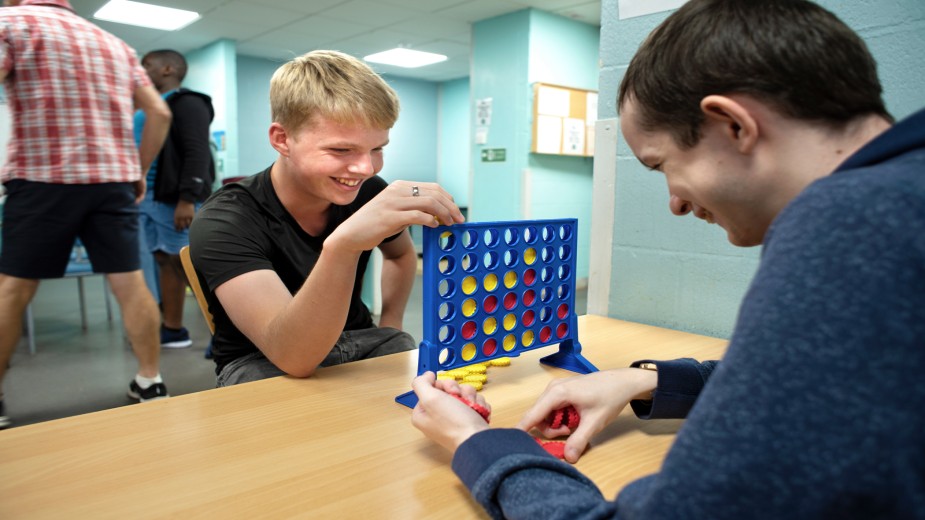 Two young lads play Connect 4 together at a Young Carers' Group